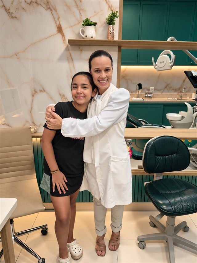 Dra. Flávia Arantes abraçando uma paciente no consultório